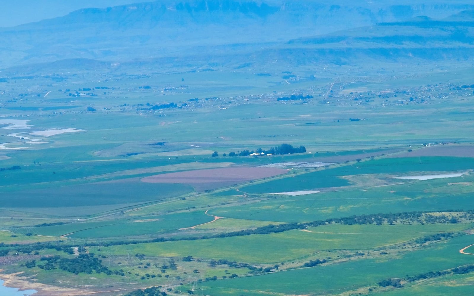 La vallée du Rift vue depuis le rebord de l'escarpement, au Kenya : cultures en damier, lac et plateaux dans la brume.